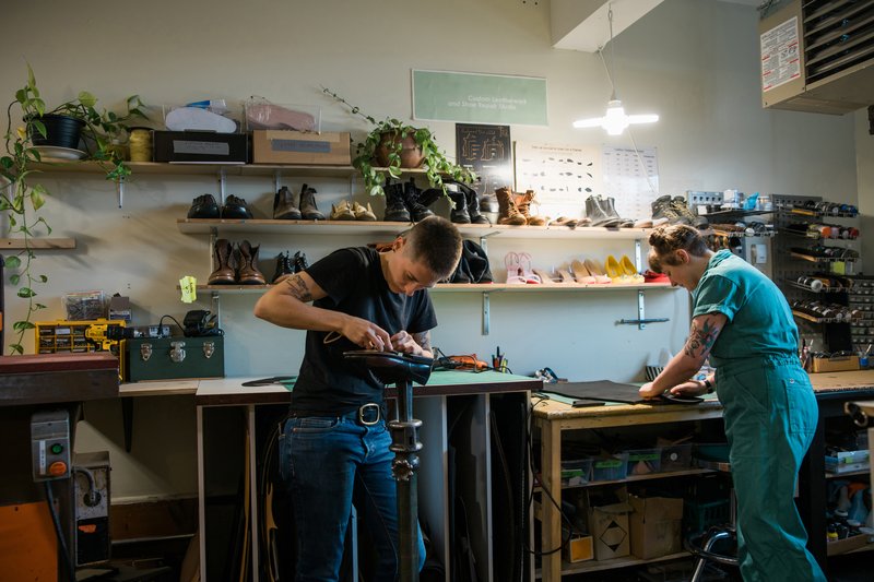 A cobbler at their workbench in a custom leather-work and shoe-repair studio
