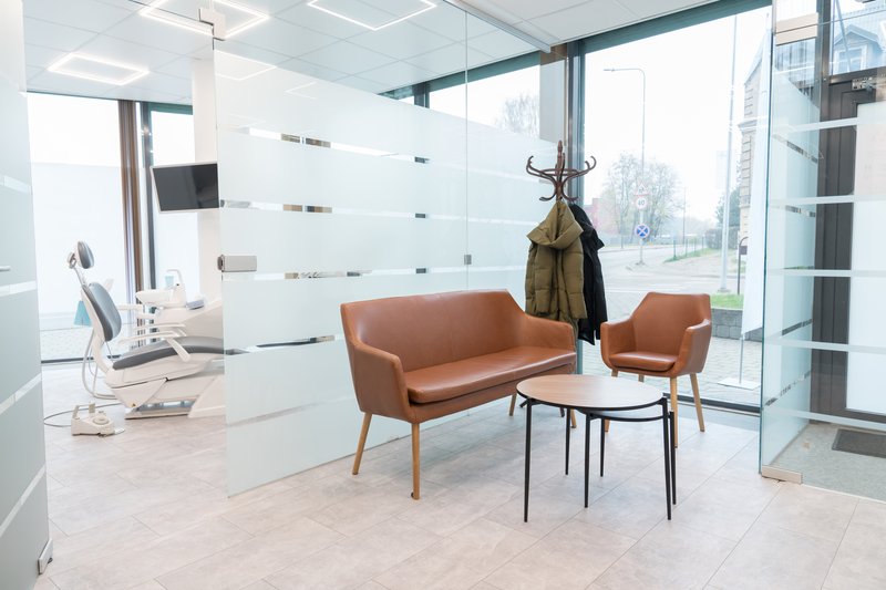 A modern dental practice waiting area with a treatment room behind frosted glass