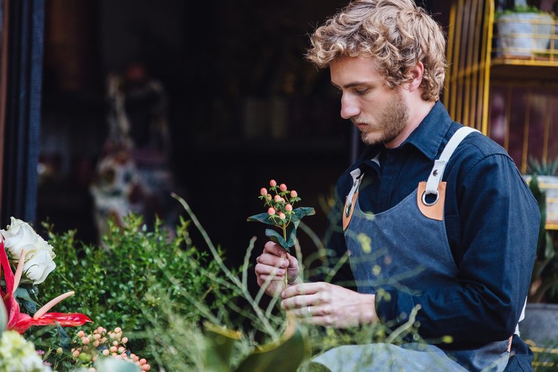 A florist arranging stems in his shop