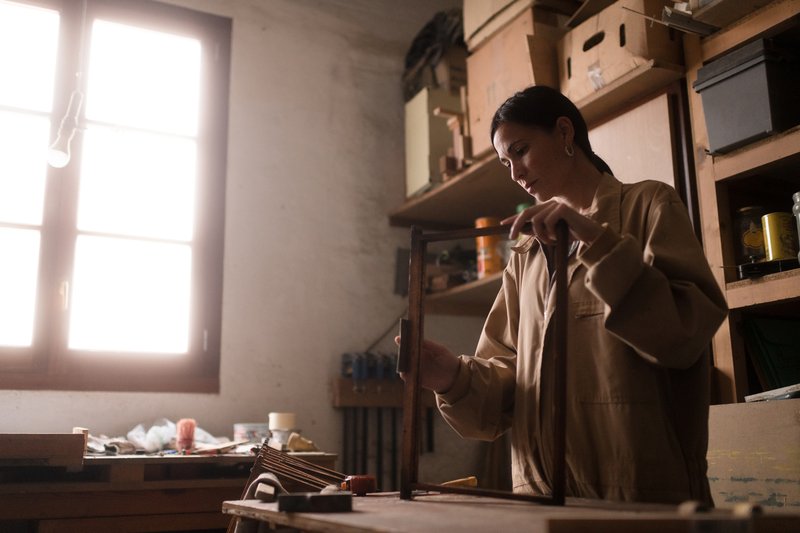 An artisan finishing a wooden frame in her workshop