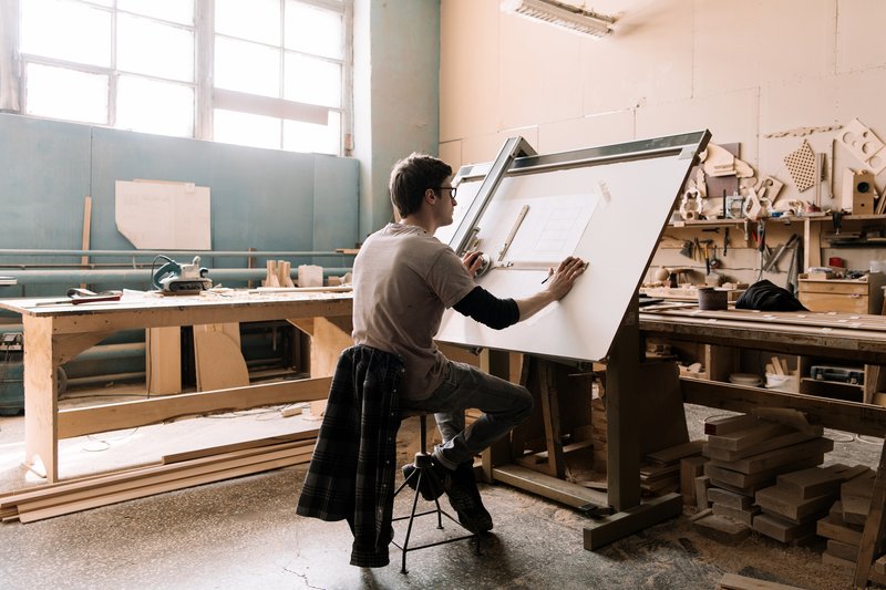 Tradesperson working at a drafting board in their joinery workshop